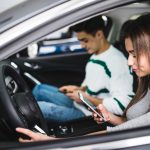 portrait of a young couple texting and driving together