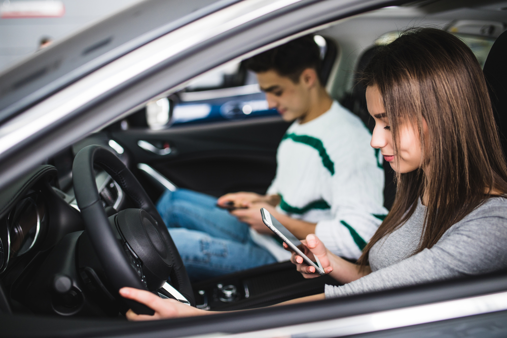 portrait of a young couple texting and driving together