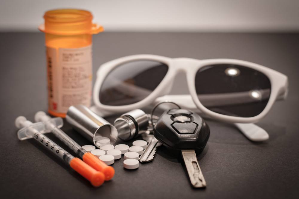 drugs, car keys, and sunglasses are strewn about in a pile